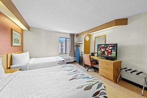 Habitación de hotel con dos camas, un escritorio con televisor, una silla, ventana con cortinas y techo de madera.