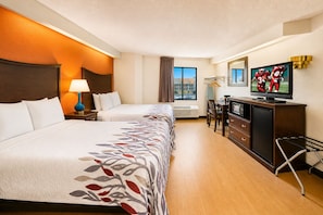A hotel room with two beds, a desk, a television, and a view of the outside. - Red Roof Inn Branson (Branson)