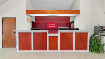 Una recepción con un fondo rojo y un cartel que indica Wi-Fi gratuito en todas las habitaciones.