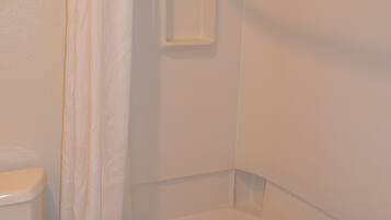 Une salle de bain équipée de toilettes, d’une baignoire et d’un rideau de douche.