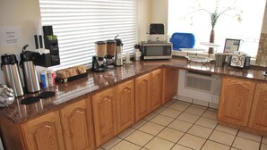 A kitchen with wooden cabinets, a coffee station, a microwave, and a toaster. - National 9 - Nephi 9 Inn (Nephi)