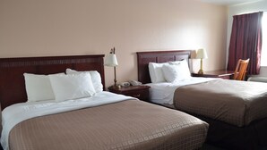 A hotel room with two beds, each with a wooden headboard, white linens, and a bedside table with a lamp and a phone. - National 9 - Nephi 9 Inn (Nephi)