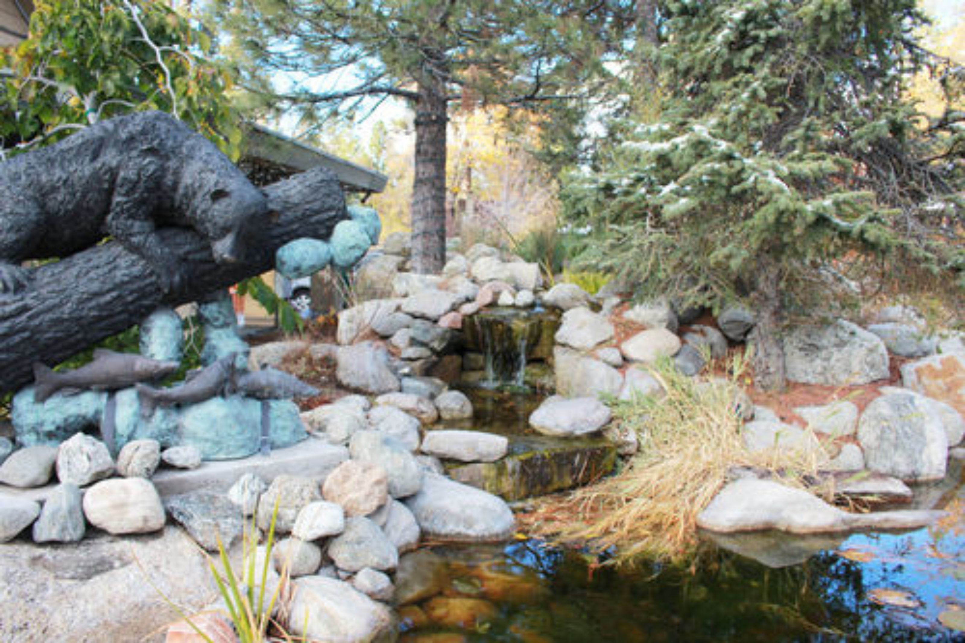 A naturalistic pond with rocks and a sculpture.