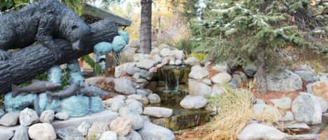 A naturalistic pond with rocks and a sculpture.