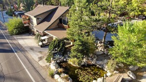 A lodge with a wooden exterior, a small pond with rocks, and a golf cart parked outside. - Bear Creek Resort (Big Bear Lake)