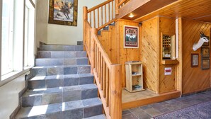 A wooden staircase with a sign for Bear Creek Resort, a mounted animal head, and a framed picture on the wall. - Bear Creek Resort (Big Bear Lake)
