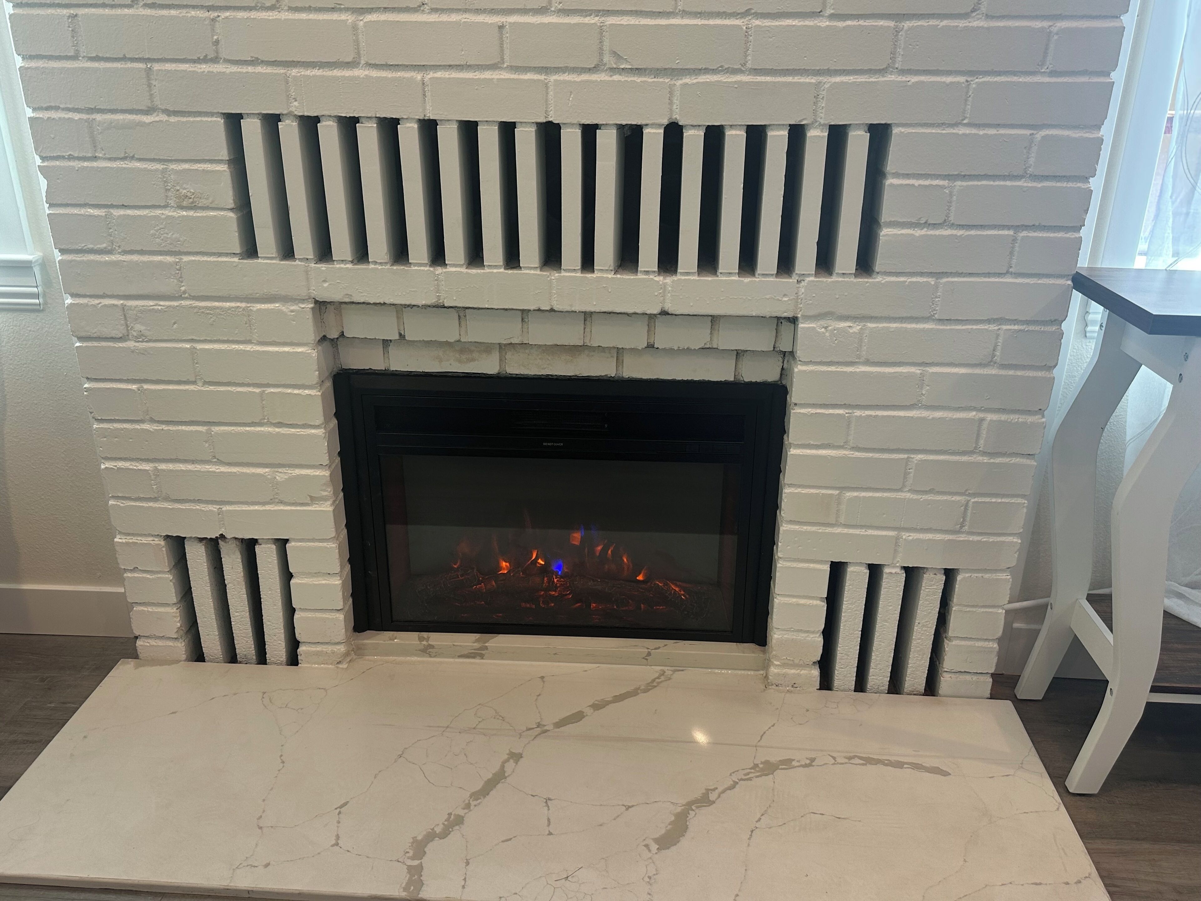 A fireplace with a white brick surround and a white marble hearth.
