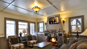 A cozy living room with a fireplace, comfortable seating, and large windows. - Bear Creek Resort (Big Bear Lake)