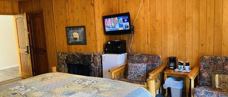 Ein Zimmer mit einem Bett, zwei Sofas, einem Fernseher, einem Kamin und einem Deckenventilator.