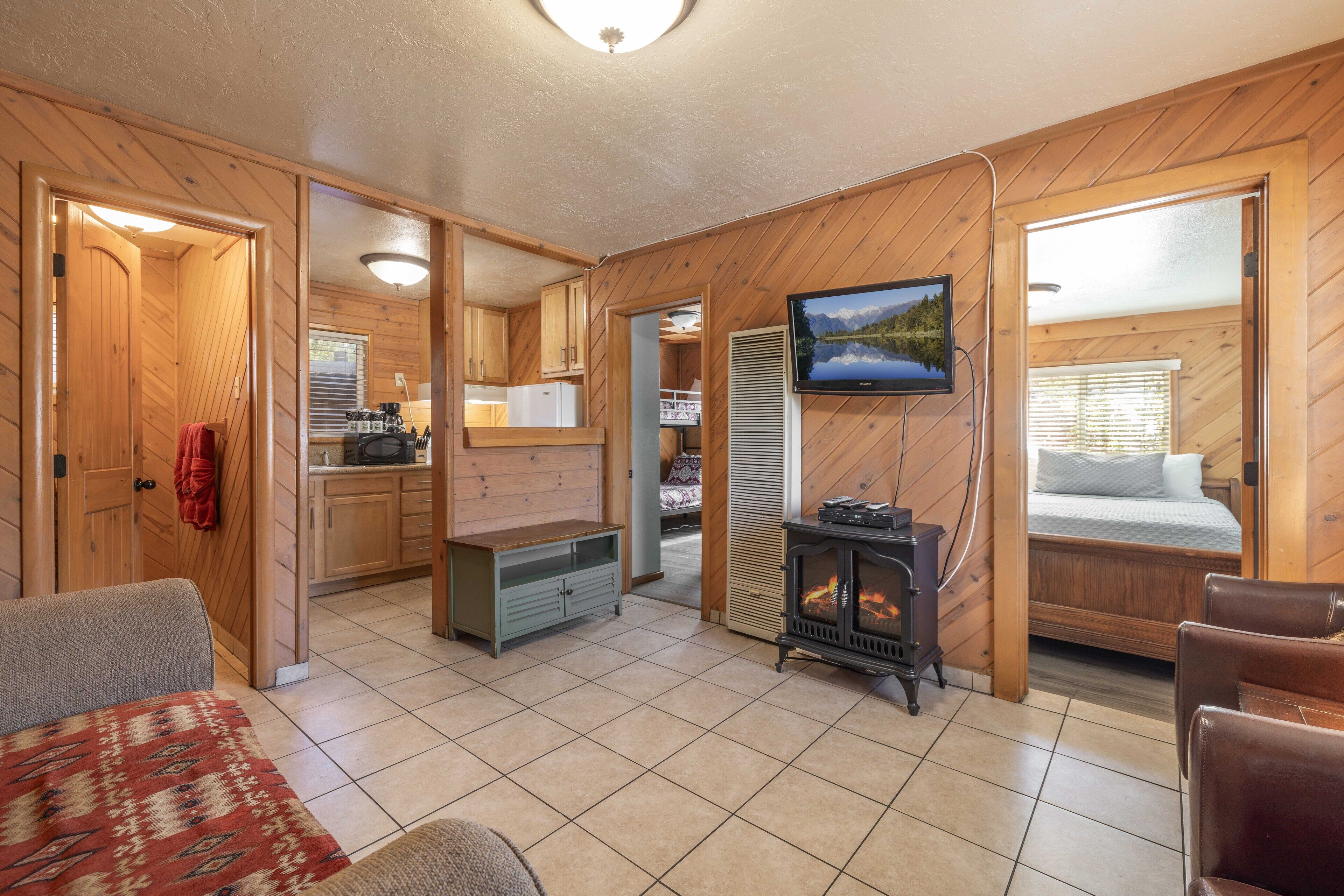 A cozy cabin interior with a living area, kitchenette, and a bedroom.