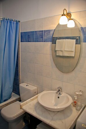 A bathroom with a toilet, sink, and mirror.