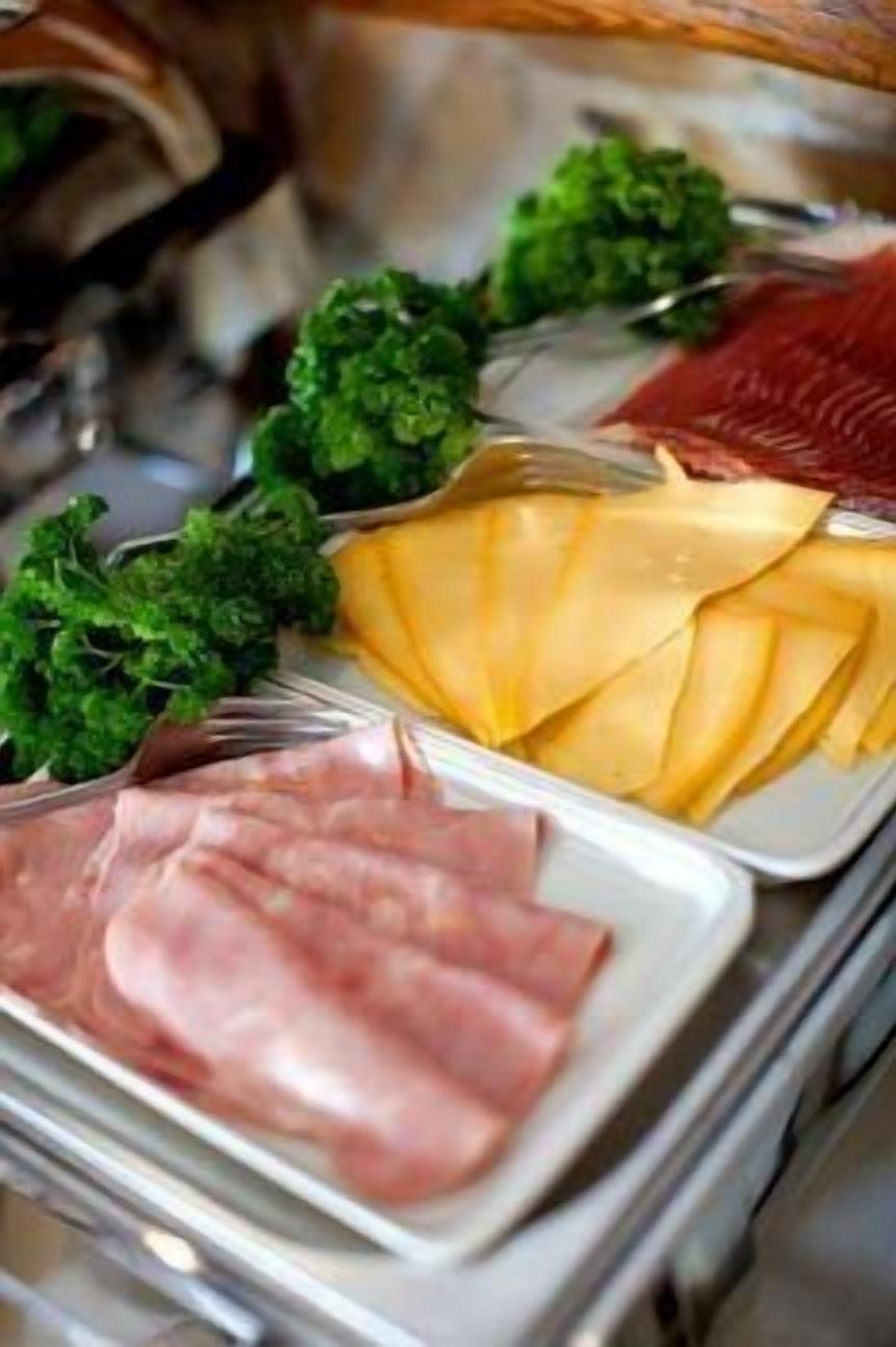 Un bufé con diversos alimentos, incluyendo carnes en rodajas, queso y vegetales.