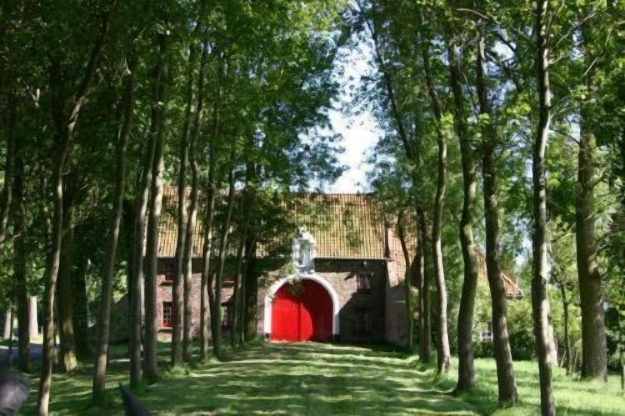 Een pad dat leidt naar een rode boog, omringd door bomen.