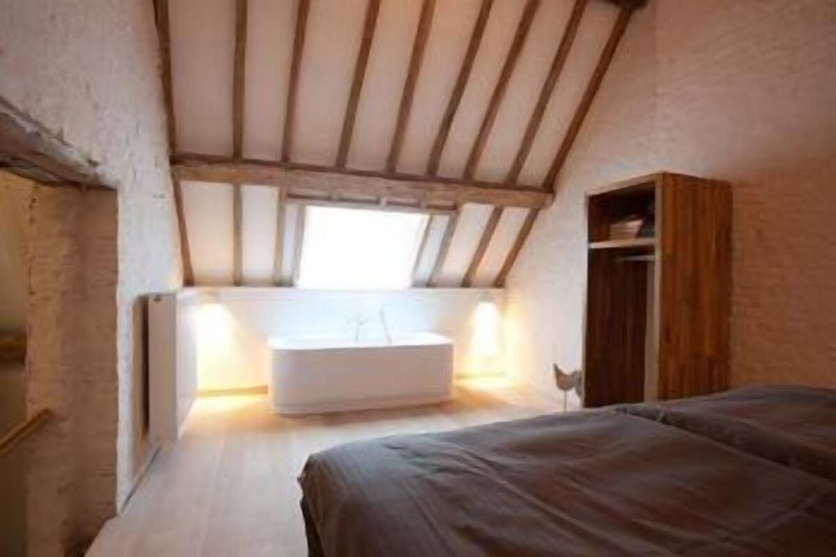 Una camera da letto con soffitto spiovente, una panca integrata e un armadio in legno.