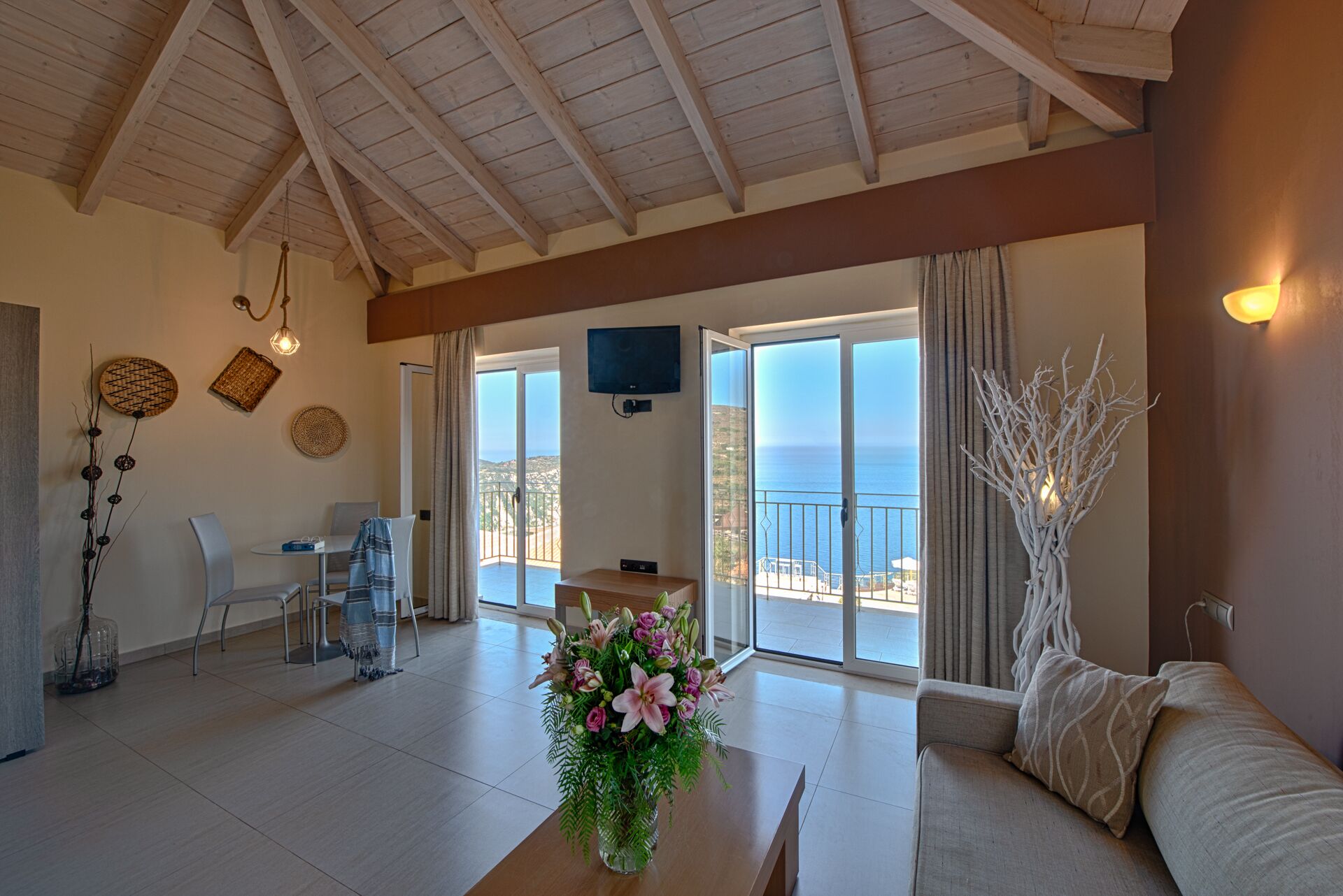 A spacious living area with a balcony overlooking the sea, a dining area, and a seating area with a sofa and table.