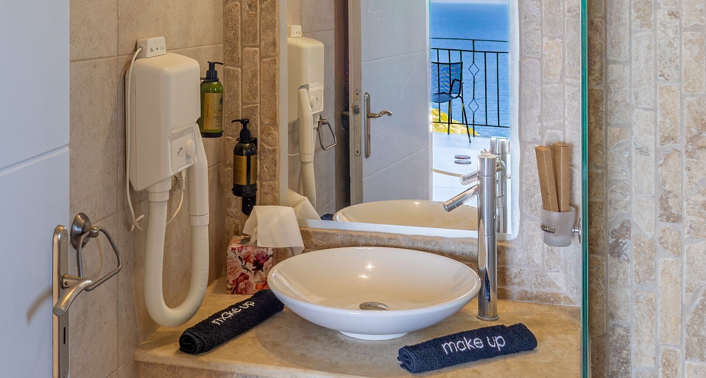 Une salle de bain avec un grand lavabo, un miroir, un téléphone et des articles de toilette.