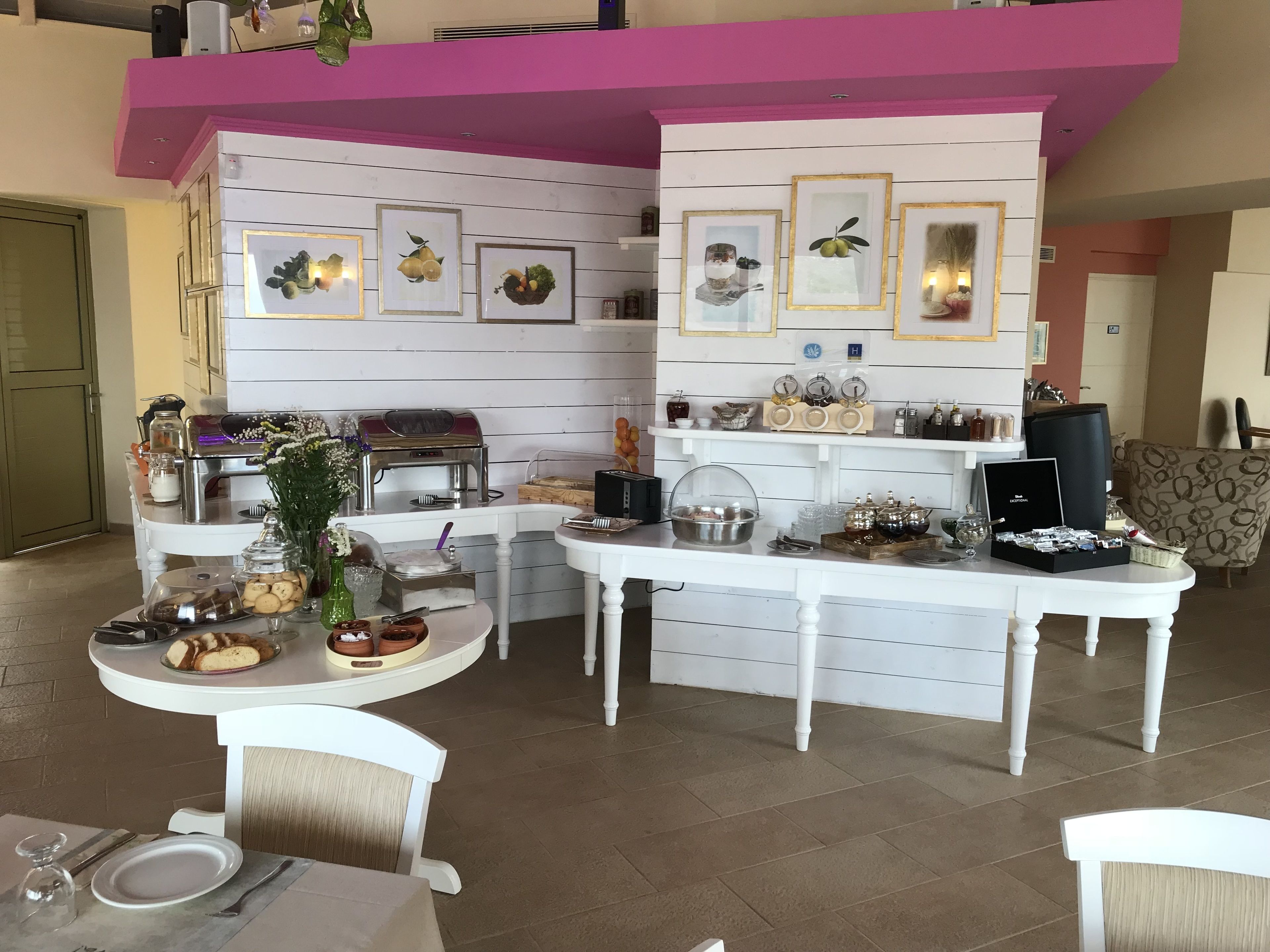 Un espace repas avec un buffet, comprenant un coin café, une variété de plats et des œuvres d’art décoratives sur les murs.