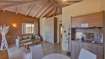 Un interior moderno con comedor, sofá, cocina con electrodomésticos de acero inoxidable y vistas por una ventana.