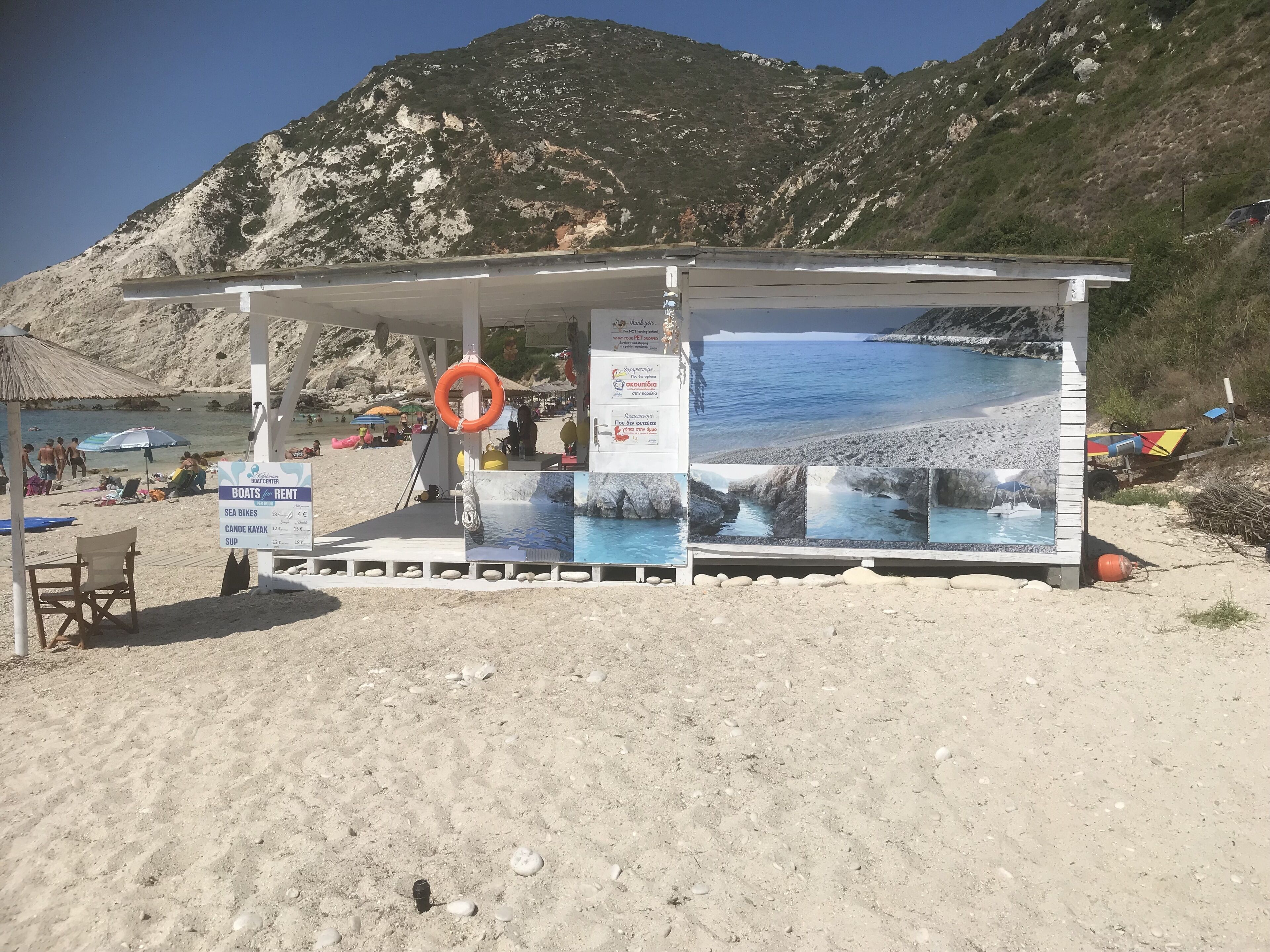 Un quiosco en la playa con un flotador, una silla y un cartel anunciando alquiler de botes y bicicletas marinas.
