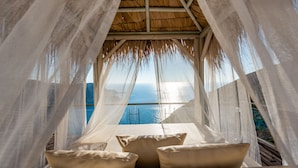 Ein Zimmer mit Meerblick, einem Reetdach und einem Tisch mit Kissen.