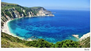 Eine Küstenlandschaft mit blauem Meer, felsigen Klippen und einer geschwungenen Küstenlinie.