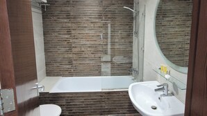 A modern bathroom with a bathtub, two sinks, and a toilet. - Le Vendôme Hotel (Amman)