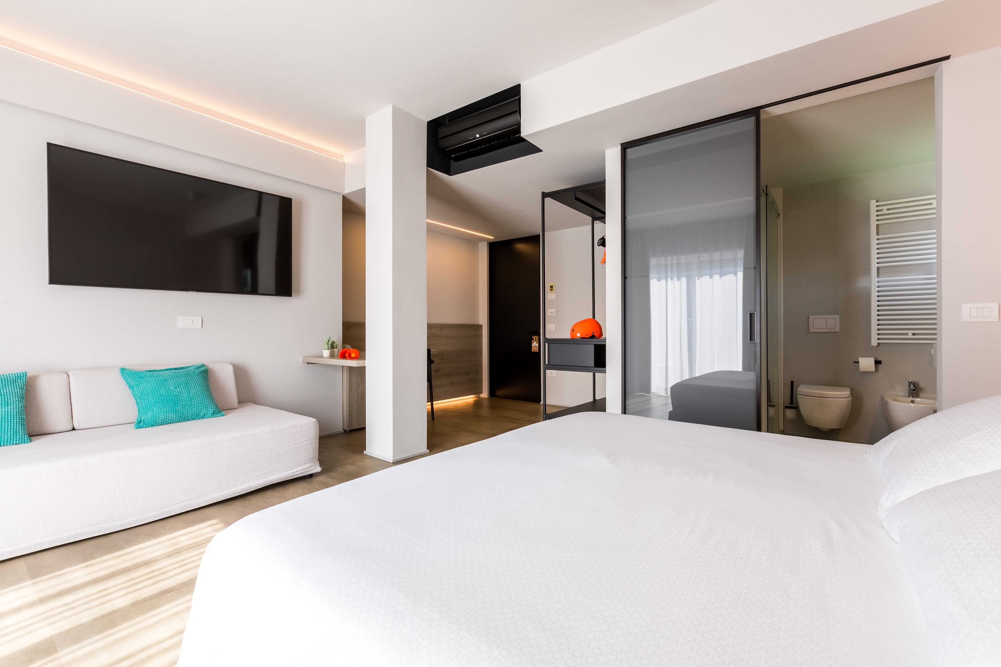 Camera d'albergo moderna con un letto grande, un divano, una TV e un bagno con il water e un lavandino.
