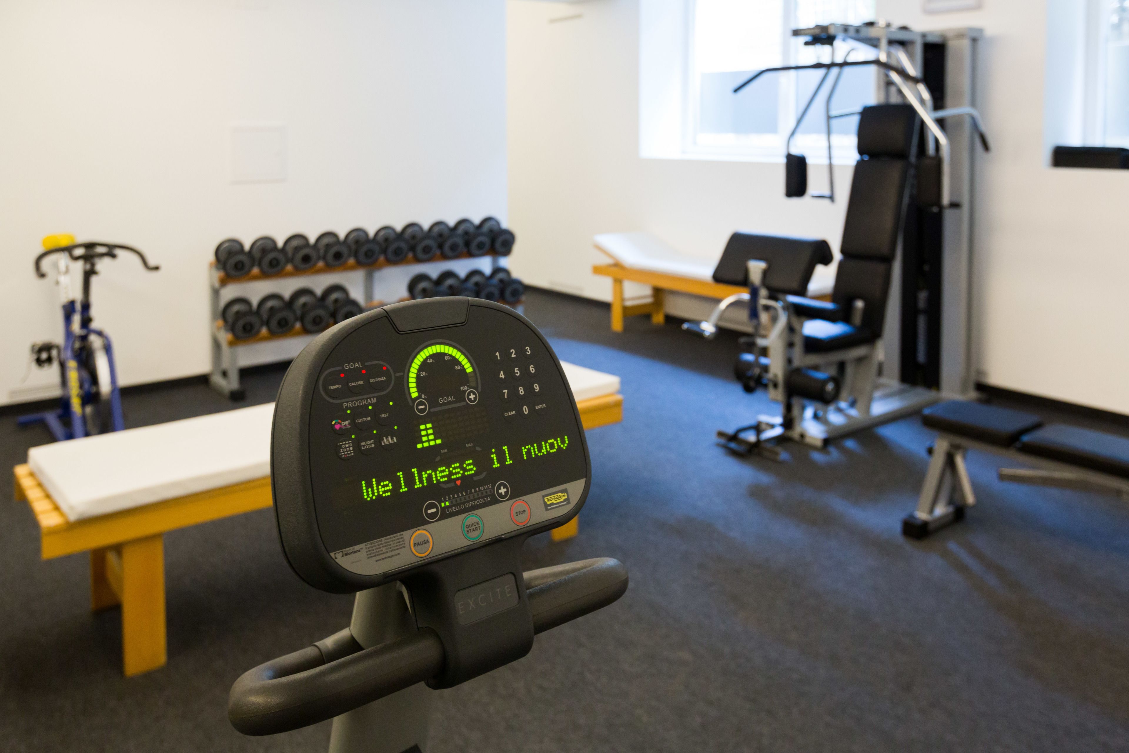 A gym with exercise equipment, dumbbells, and a bench.