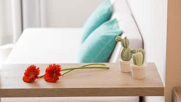 Ein Holztischchen mit zwei roten Blumen und zwei kleinen Sukkulenten.