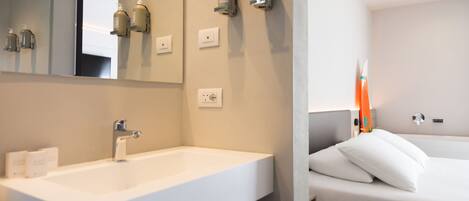 Un baño moderno con un lavamanos grande, un espejo y artículos de tocador en la pared.
