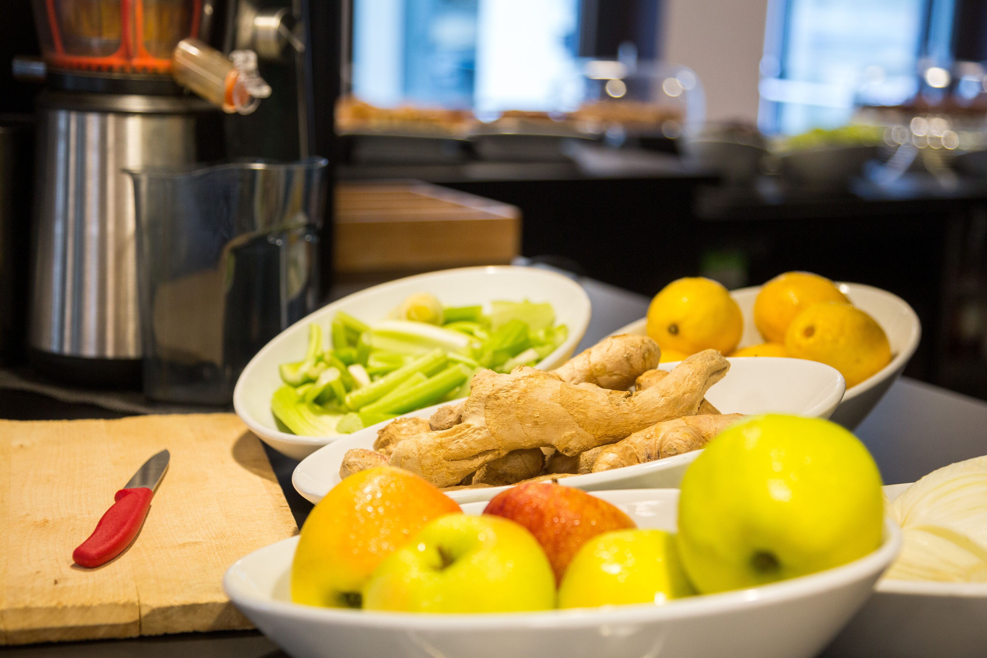 Uma bancada de cozinha com frutas e legumes diversos, uma tábua de corte e uma faca.