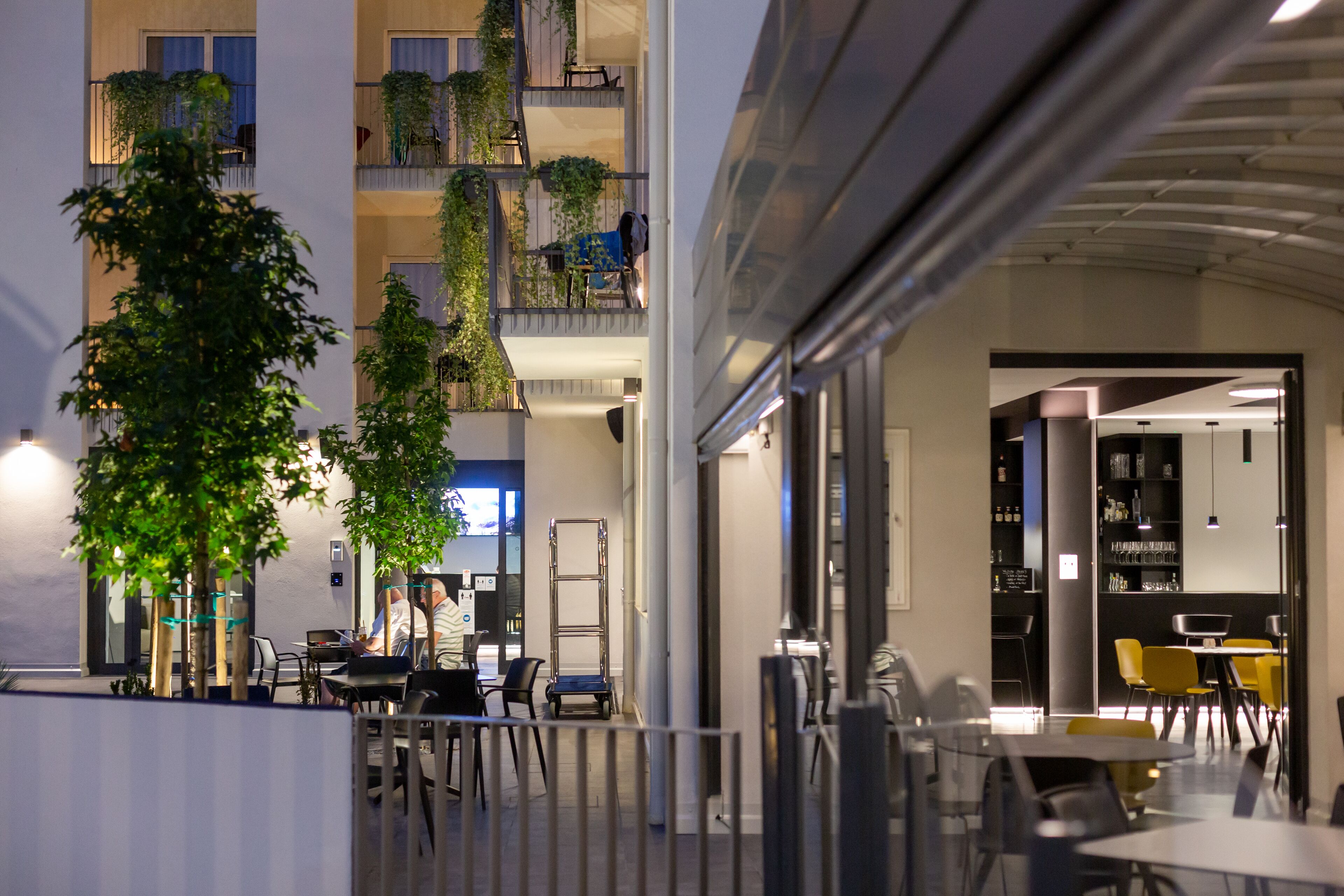 A modern indoor space with multiple levels, outdoor seating, and indoor dining areas.