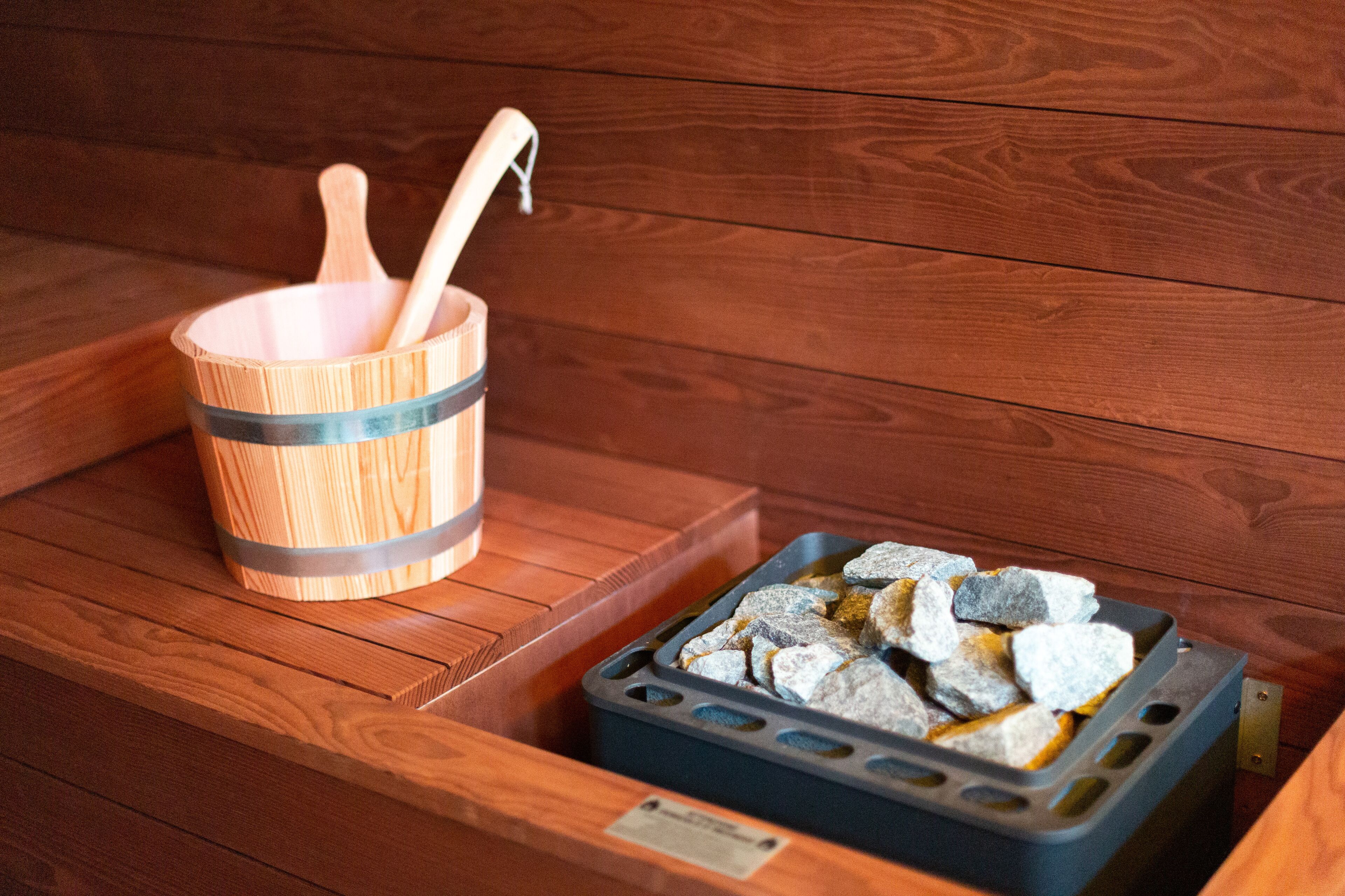 A wooden bench with a wooden bucket and a tray of stones.