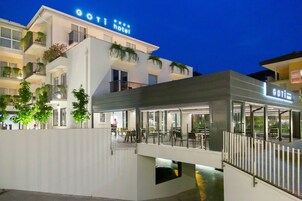 Un hotel moderno con un llamativo letrero que dice 'Goti Hotel', un área de estar al aire libre y balcones con plantas.