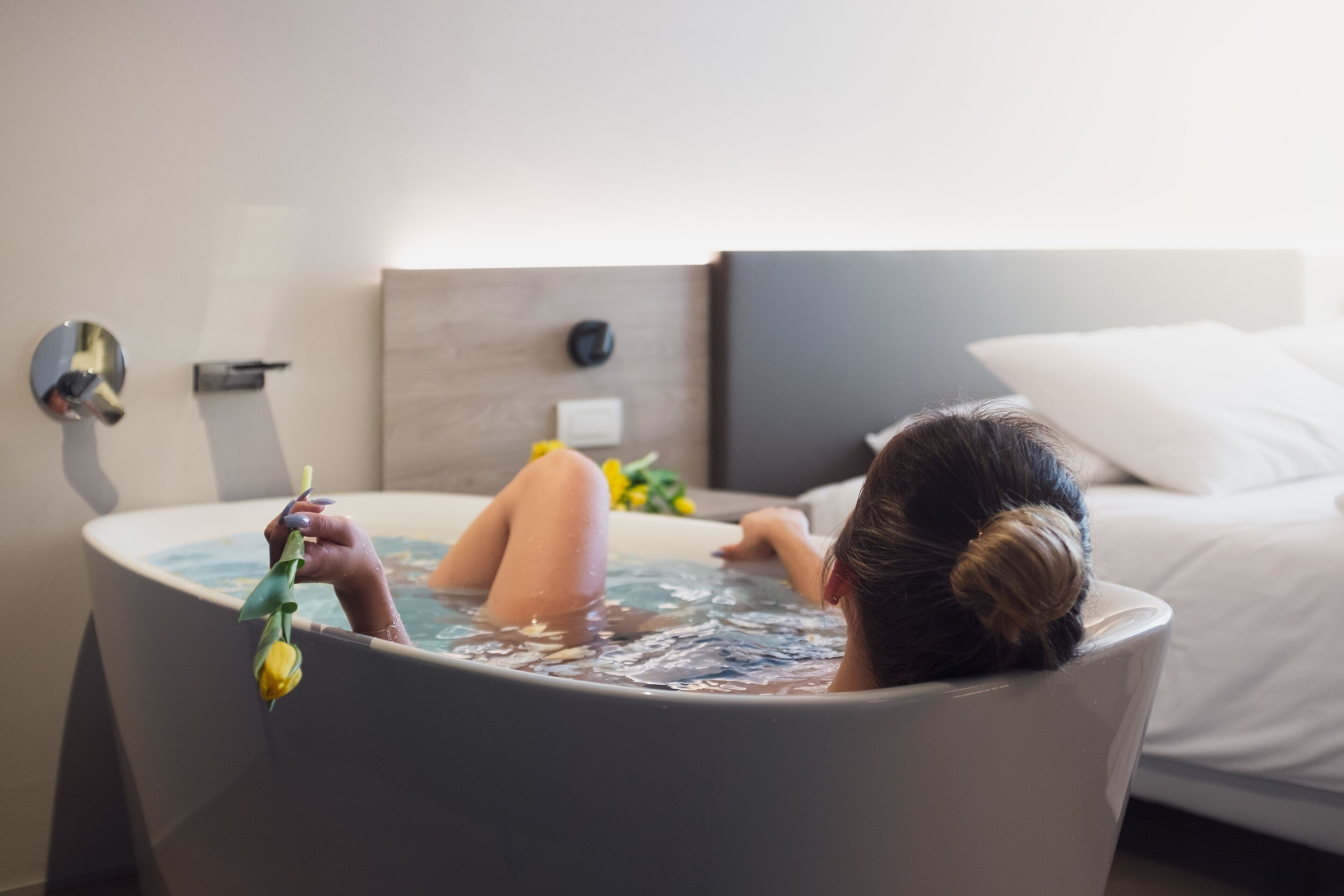 A person relaxing in a bathtub with a flower.