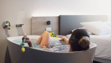 A person relaxing in a bathtub with a flower.