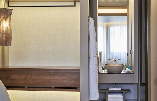 A modern bathroom with a large mirror, a wooden vanity, a large bowl sink, and a hanging towel.