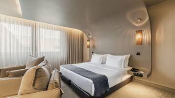 Una habitación de hotel moderna con una cama grande, un sofá y un escritorio con una lámpara.