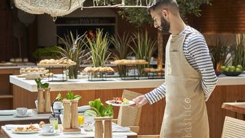 Un bufé de desayuno con diversas opciones de comida y un camarero sirviendo un plato.
