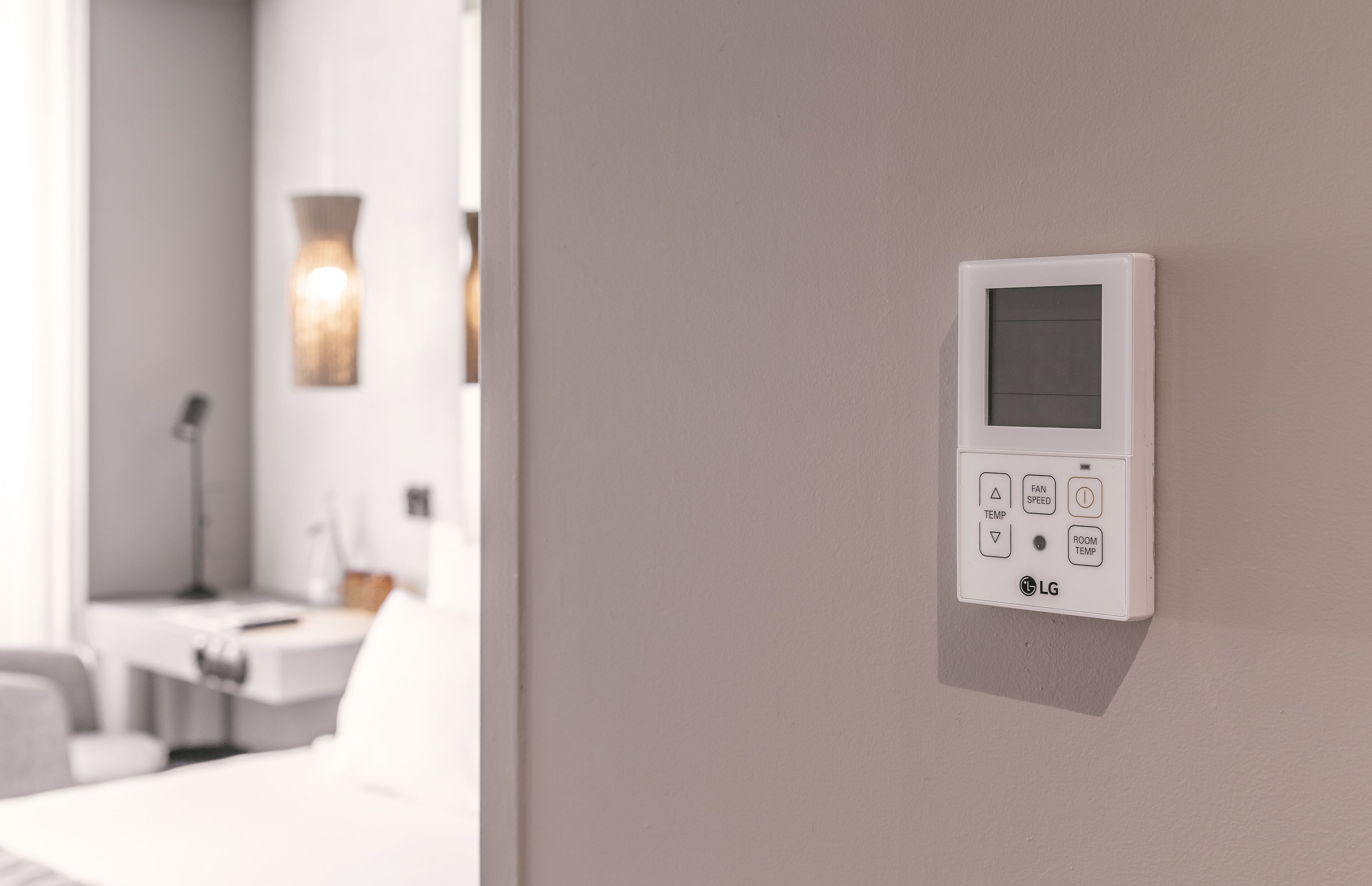 A wall-mounted LG thermostat with temperature and fan speed controls.