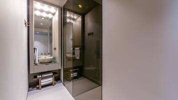 A modern bathroom with a large mirror, a sink, and a glass-enclosed shower.