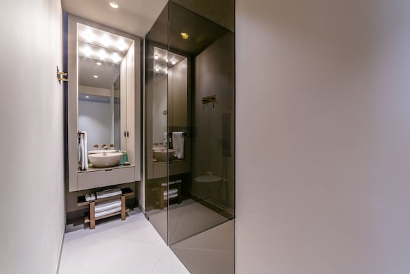 Un baño moderno con un espejo grande, un lavabo y una ducha con cerramiento de vidrio.
