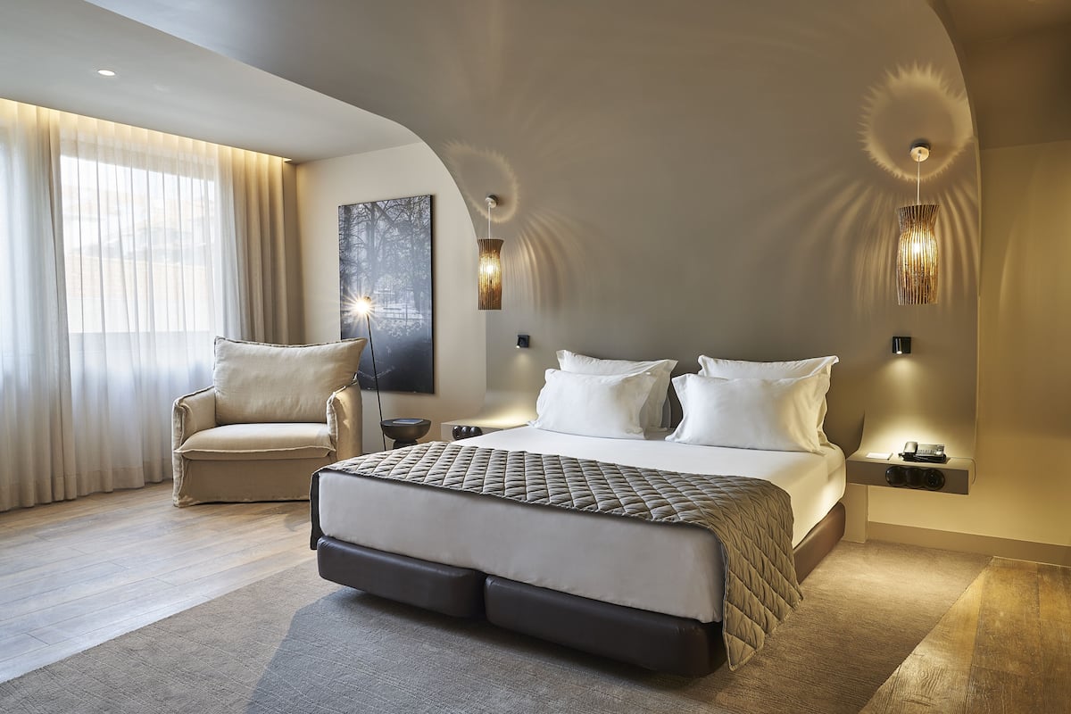 A modern bedroom with a large bed, a chair, and a painting on the wall.