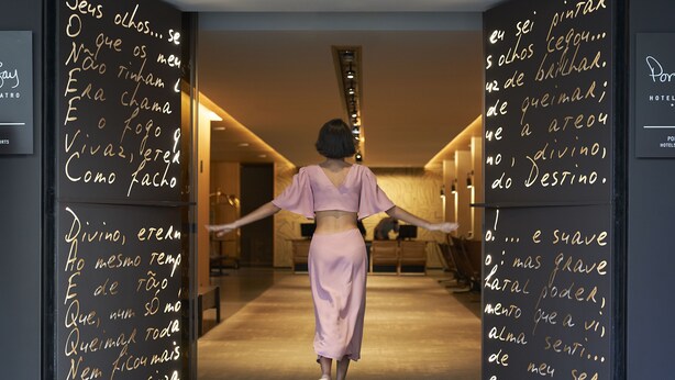A person walking through a hallway with walls covered in handwritten text. - PortoBay Teatro (Porto)