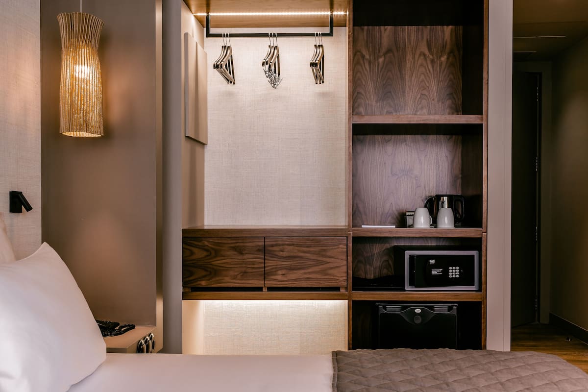 A modern hotel room with a bed, a built-in coffee maker, a microwave, and a small refrigerator.