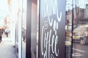 A sign with the text "I drink the coffee" on a glass window.