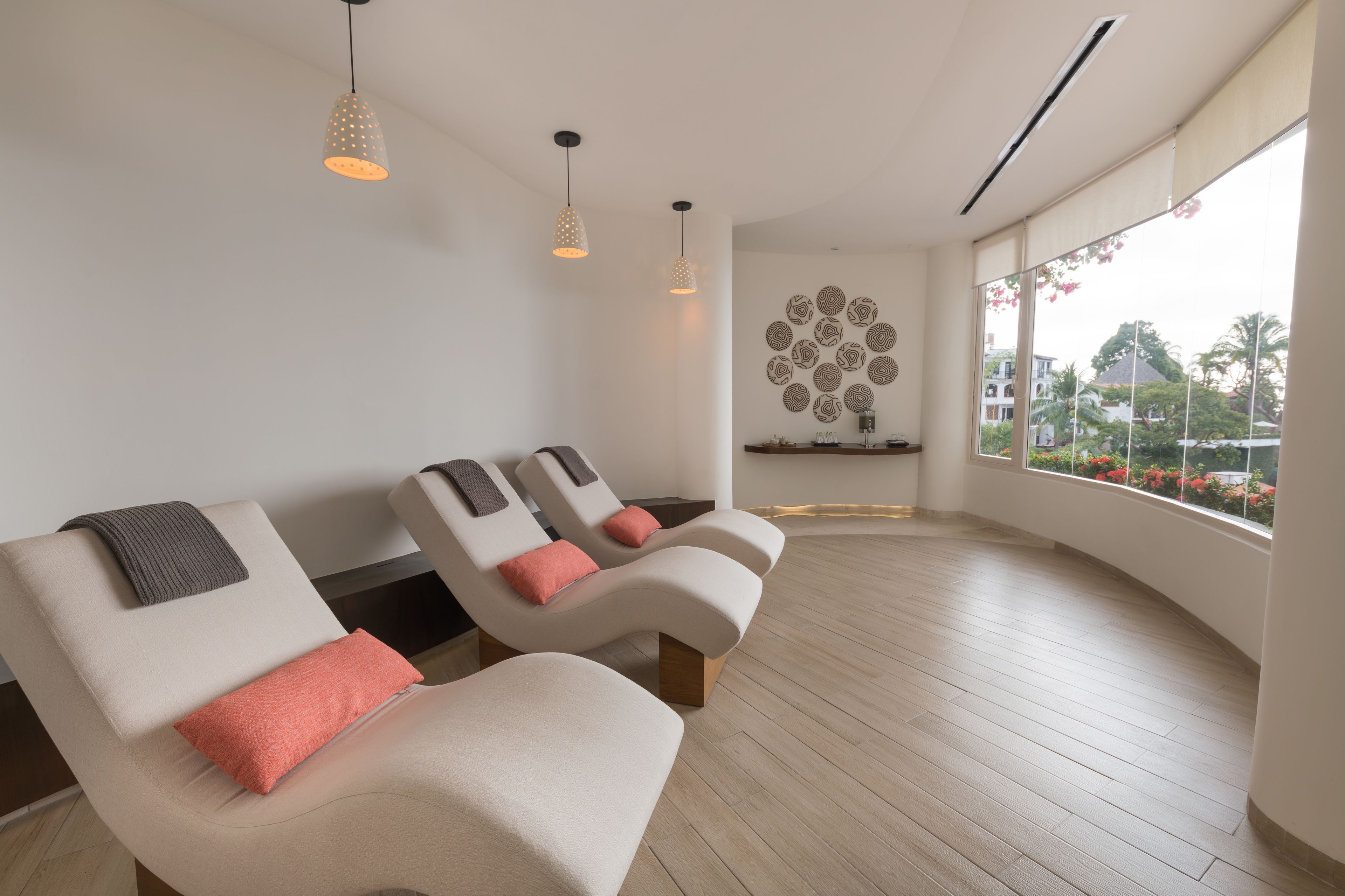 Un cuarto de spa con dos sillones de masaje, piso de madera y un ventanal con vista a edificios y árboles.