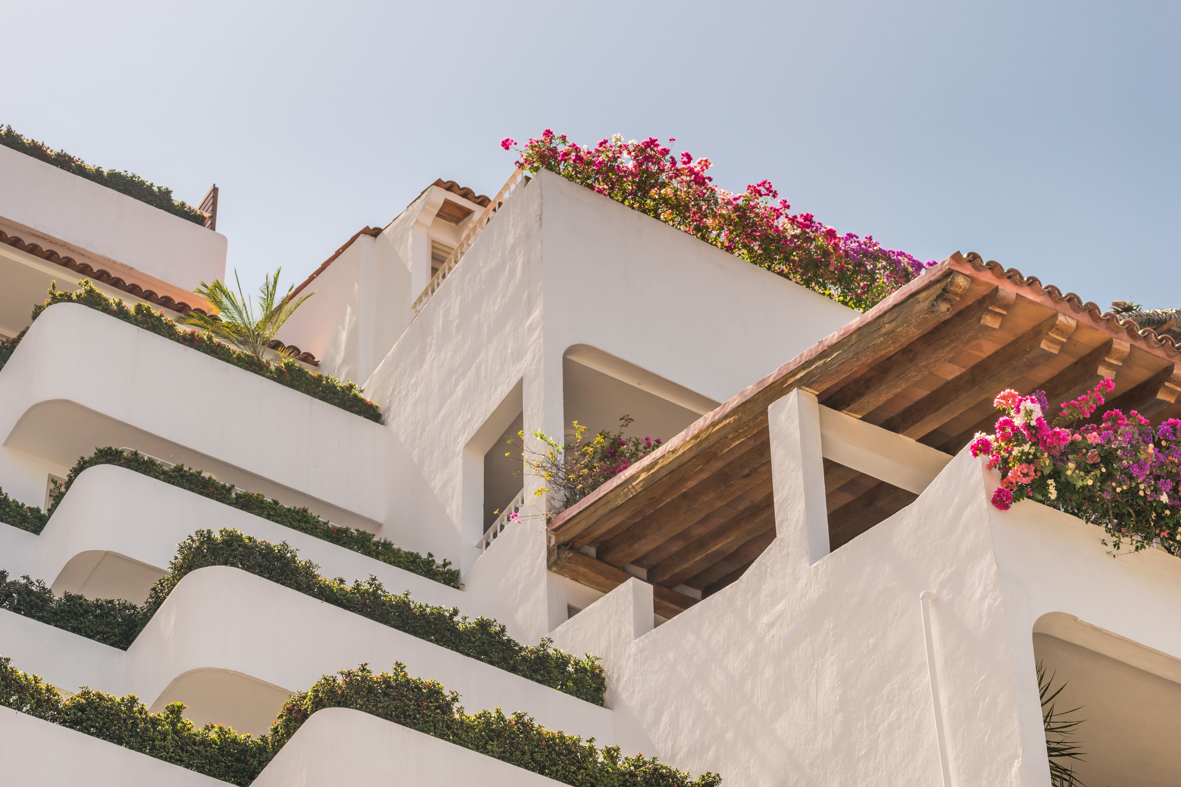 A multi-story building with balconies adorned with greenery and flowers.