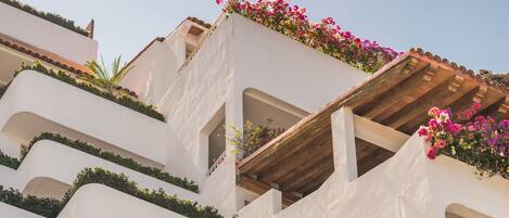 A multi-story building with balconies adorned with greenery and flowers.