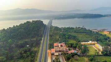 An aerial view of a coastal area with a bridge, lush greenery, and a hotel with multiple buildings.
